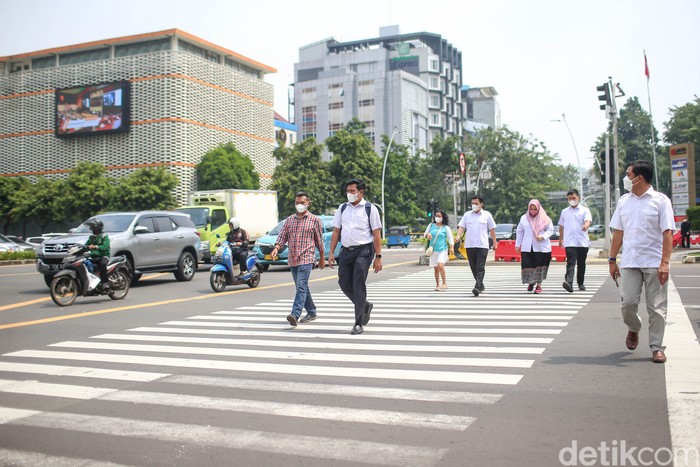 Sejumlah pekerja tengah melintas di pelican cross di kawasan Sarinah, Thamrin, Jakarta, Rabu (11/5/2022).