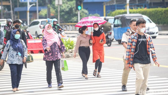 Teriknya Jakarta di Tengah Fenomena Cuaca Panas Sejumlah pekerja tengah melintas di pelican cross di kawasan Sarinah, Thamrin, Jakarta, Rabu (11/5/2022).