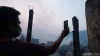 Seorang warga terlihat mengambil gambar kebakaran menggunakan gadget miliknya.