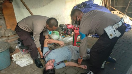 Anggota Polisi saat mengevakuasi turis Rusia yang mendadak pingsan di emperan toko buah