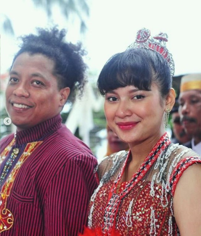 Acara syukuran pernikahan tersebut diadakan secara outdoor di tepi pantai di Buton. Terlihat Arie dan Indah tampil kompak mengenakan busana adat Sulawesi bernuansa merah. Dengan poni depan dan rambut yang diikat ke atas, Indah tampil mempesona. Foto: Instagram/@arie_kriting