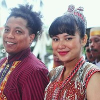 Acara syukuran pernikahan tersebut diadakan secara outdoor di tepi pantai di Buton. Terlihat Arie dan Indah tampil kompak mengenakan busana adat Sulawesi bernuansa merah. Dengan poni depan dan rambut yang diikat ke atas, Indah tampil mempesona. Foto: Instagram/@arie_kriting