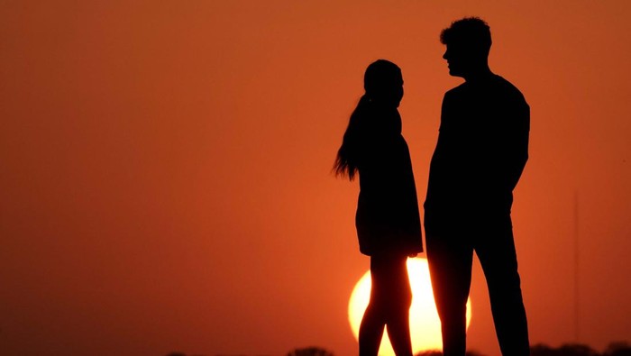 A woman is silhouetted against the sky as the sun sets Wednesday, May 11, 2022, in Kansas City, Mo. Sunsets have been more vibrant than normal as smoke from a large wildfire in New Mexico drifts eastward across the midwest. (AP Photo/Charlie Riedel)