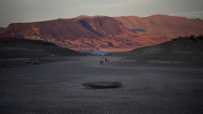 Ngeri, Kerangka Korban Pembunuhan Muncul dari Danau yang Mengering di AS A formerly sunken boat sits on cracked earth hundreds of feet from what is now the shoreline on Lake Mead at the Lake Mead National Recreation Area, Monday, May 9, 2022, near Boulder City, Nev. Lake Mead is receding and Sin City is awash with mob lore after a second set of human remains emerged within a week from the depths of the drought-stricken Colorado River reservoir just a short drive from the Las Vegas Strip. (AP Photo/John Locher)