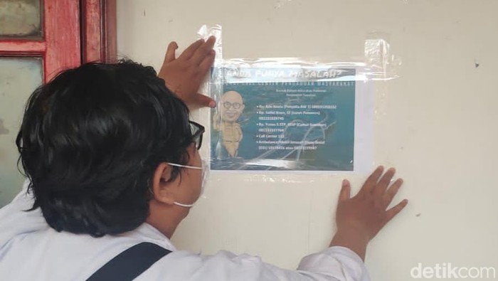 Petugas kecamatan Sawahan memasang nomor kontak ASN yang siap membantu warga di setiap RW.