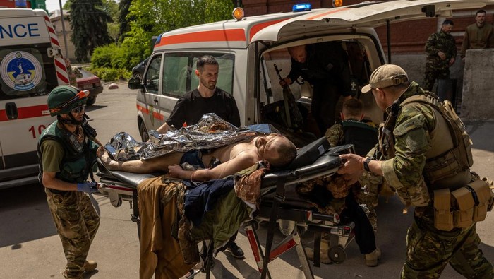 Sibuknya Rumah Sakit Kecil di Ukraina, Jadi Garda Terdepan Penolong Korban A nurse carries a stretcher past an ambulance which is carrying the body of a dead Ukrainian soldier, amid Russia's invasion in Ukraine, outside the emergency room at a hospital in Bakhmut, Donetsk region, Ukraine, May 5, 2022. REUTERS/Jorge Silva SEARCH