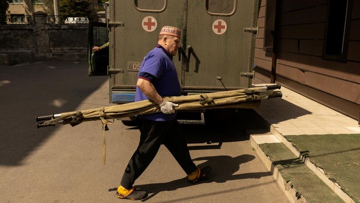 Sibuknya Rumah Sakit Kecil di Ukraina, Jadi Garda Terdepan Penolong Korban A nurse carries a stretcher past an ambulance which is carrying the body of a dead Ukrainian soldier, amid Russia's invasion in Ukraine, outside the emergency room at a hospital in Bakhmut, Donetsk region, Ukraine, May 5, 2022. REUTERS/Jorge Silva SEARCH