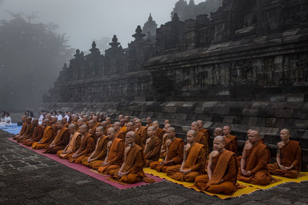 MAGELANG, CENTRAL JAVA, INDONESIA - MAY 18: Buddhist monks pray at Borobudur temple during celebrations for Vesak Day on May 18, 2019 in Magelang, Central Java, Indonesia. Buddhists in Indonesia celebrate Vesak at the Borobudur temple annually, which makes it the most visited tourist attraction in Indonesia. It is observed during the full moon in May or June, with the ceremony centered at three Buddhist temples by walking from Mendut to Pawon and ending at Borobudur. The stages of life of Buddhism's founder, Gautama Buddha, which are celebrated at Vesak are his birth, enlightenment to Nirvana, and his passing (Parinirvana). (Photo by Ulet Ifansasti/Getty Images)