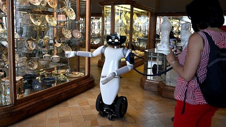 Canggih! Robot 5G Jadi Pemandu Museum di Italia A photo shows the humanoid robot R1, designed by the Italian Institute of Technology, serving as a virtual guide for visitors, holding a guided tour for tourists in the ceramic room at the Palazzo Madama museum in Turin on May 12, 2021. - The experimentation is part of the European Union funded project 5G-TOURS that aims to test and use 5G technologies to provide useful, efficient and reliable services to citizens and tourists. The robot is able to describe the works and answer questions relating to the author or the historical period to which they belong. - RESTRICTED TO EDITORIAL USE - MANDATORY MENTION OF THE ARTIST UPON PUBLICATION - TO ILLUSTRATE THE EVENT AS SPECIFIED IN THE CAPTION (Photo by MARCO BERTORELLO / AFP) / RESTRICTED TO EDITORIAL USE - MANDATORY MENTION OF THE ARTIST UPON PUBLICATION - TO ILLUSTRATE THE EVENT AS SPECIFIED IN THE CAPTION / RESTRICTED TO EDITORIAL USE - MANDATORY MENTION OF THE ARTIST UPON PUBLICATION - TO ILLUSTRATE THE EVENT AS SPECIFIED IN THE CAPTION (Photo by MARCO BERTORELLO/AFP via Getty Images)
