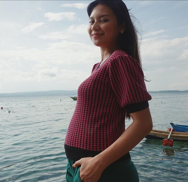 Dengan mengenakan atasan merah muda bermotif dan celana hijau, Indah yang sedang berada di pantai itu terlihat begitu bahagia. Tanpa pulasan makeup, wajahnya tampak glowing dan cantik mempesona. Foto: Instagram/@indahpermatas