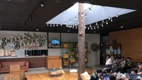 Area semi outdoor Society Coffee House. Dipenuhi mural, area lesehan dan permainan atap terbuka di bagian tengah.