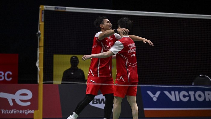 Indonesias Kevin Sukamuljo (R) and Mohammad Ahsan (L) hug after defeating Japans Takuro Hoki and Yugo Kobayashi during the semifinals of the Thomas and Uber Cup badminton tournament in Bangkok on May 13, 2022. (Photo by Lillian SUWANRUMPHA / AFP)