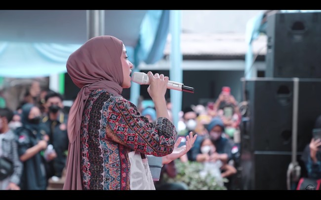 Sementara bagian kiri depan gamisnya ditambal dengan kain tulle bermotif bunga. Nissa Sabyan memadukan gamis tersebut dengan rok plisket berwarna coklat dan sneakers bermotif checkerboard dari Vans. Foto: dok. YouTube SABYAN