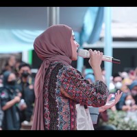 Sementara bagian kiri depan gamisnya ditambal dengan kain tulle bermotif bunga. Nissa Sabyan memadukan gamis tersebut dengan rok plisket berwarna coklat dan sneakers bermotif checkerboard dari Vans. Foto: dok. YouTube SABYAN