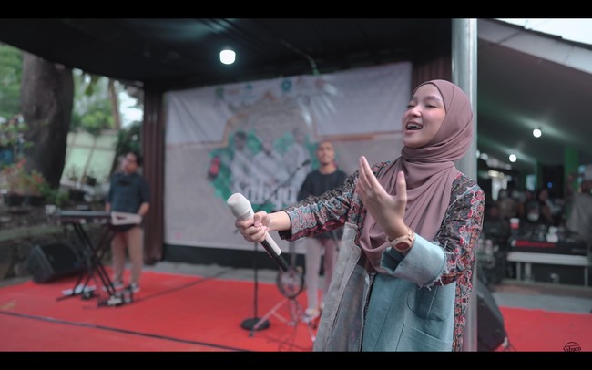 Gamis yang dikenakan Nissa Sabyan pun terlihat memiliki potongan asimetris. Lengan kiri bajunya masih memiliki aksen jeans. Untuk melengkapi penampilannya, dia memakai jam tangan berbahan kayu koleksi brand lokal dengan kerudung berwarna pink. Foto: dok. YouTube SABYAN
