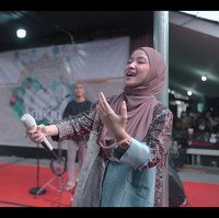 Gamis yang dikenakan Nissa Sabyan pun terlihat memiliki potongan asimetris. Lengan kiri bajunya masih memiliki aksen jeans. Untuk melengkapi penampilannya, dia memakai jam tangan berbahan kayu koleksi brand lokal dengan kerudung berwarna pink. Foto: dok. YouTube SABYAN