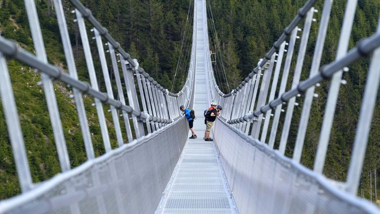 Visitors cross a suspension bridge for the pedestrians that is the longest such construction in the world shortly after its official opening at a mountain resort in Dolni Morava, Czech Republic, Friday, May 13, 2022. The 721-meter (2,365 feet) long bridge is built at the altitude of more than 1,100 meters above the sea level. It connects two ridges of the mountains up to 95 meters above a valley between them. (AP Photo/Petr David Josek)