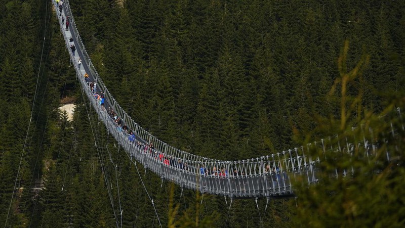 Visitors cross a suspension bridge for the pedestrians that is the longest such construction in the world shortly after its official opening at a mountain resort in Dolni Morava, Czech Republic, Friday, May 13, 2022. The 721-meter (2,365 feet) long bridge is built at the altitude of more than 1,100 meters above the sea level. It connects two ridges of the mountains up to 95 meters above a valley between them. (AP Photo/Petr David Josek)