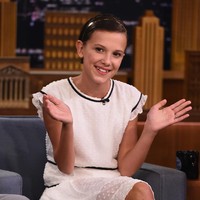 Millie Bobby Brown menghadiri talkshow The Tonight Show Starring Jimmy Fallon pada 31 Agustus 2016 untuk mempromosikan musim pertama Stranger Things yang baru diluncurkan. Millie yang rambutnya dicukur habis untuk perannya sebagai Eleven muncul dengan gaya ala ABG dalam balutan dress putih dan sneakers.  (Foto: Getty Images for NBC/Theo Wargo)