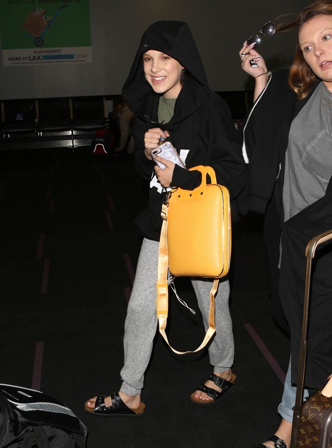 Millie Bobby Brown saat dipotret paparazzi pada 2017. Di luar karpet merah dan acara formal, aktris yang terlahir dengan gangguan pendengaran sebelah ini lebih suka mengandalkan gaya yang super kasual dengan hoodie dan sandal favoritnya. (Foto: GC Images/SMXRF/Star Max)
