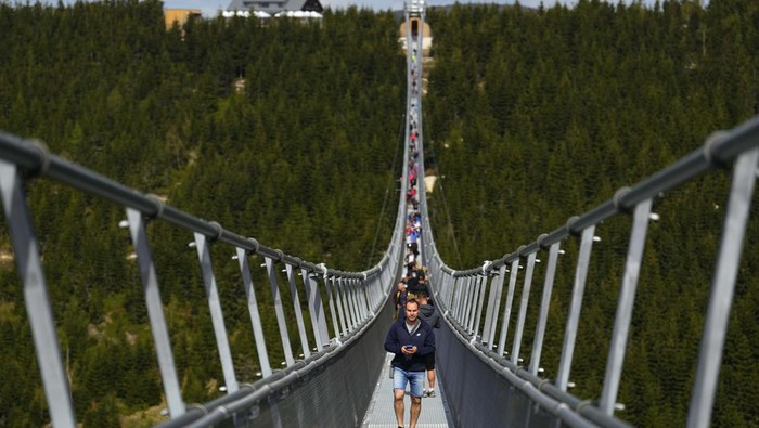 A worker dies some final touches at a suspension bridge for the pedestrians that is the longest such construction in the world a day before its official opening at a mountain resort in Dolni Morava, Czech Republic, Thursday, May 12, 2022. The 721-meter (2,365 feet) long bridge is built at the altitude of more than 1,100 meters above the sea level. It connects two ridges of the mountains up to 95 meters above a valley between them. (AP Photo/Petr David Josek)
