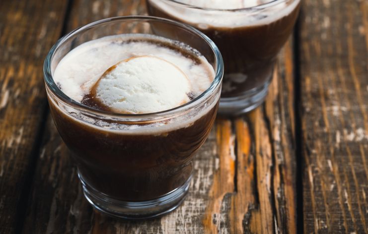 Cold brew coffee with ice cream in glasses on wooden rustic table, delicious summer dessert
