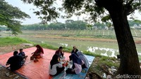 Sejumlah warga menyantap makanan yang dibeli dari para pedagang yang berjualan di pinggir Banjir Kanal Timur (BKT), Jakarta, Senin (16/5/2022).