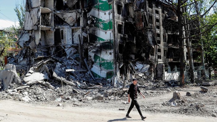 A man walks past a residential building destroyed during Ukraine-Russia conflict in the southern port city of Mariupol, Ukraine May 12, 2022. REUTERS/Alexander Ermochenko
