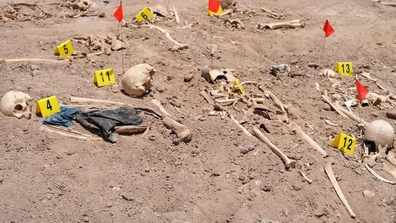 Sisa-sisa mayat yang ditemukan di kuburan massal era Saddam Hussein Human remains exhumed from a mass grave by Iraqi authorities, lie on the ground near the southern city of Najaf, on May 14, 2022. (AFP)