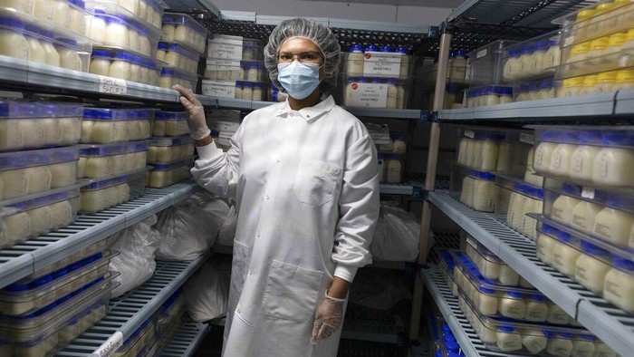 Lab manager Shantel Collins stands in the freezer between shelves of pasteurized breast milk at Mothers' Milk Bank of the Northeast, Friday, May 13, 2022, in Newton, Mass. (AP Photo/Michael Dwyer)
