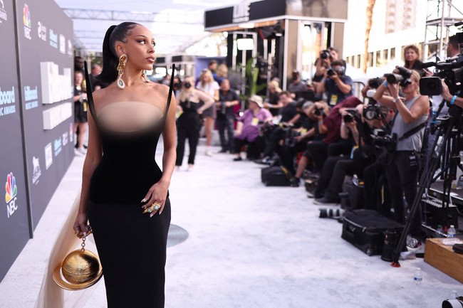 Seperti dikutip dari People, Doja Cat tampil ala high fashion di karpet merah Billboard Music Awards 2022. Dia mengenakan gaun hitam yang merupakan koleksi couture desainer Italia, Schiaparelli. Gaun tersebut memiliki detail lancip di sisi kiri dan kanan atasnya dan tidak memiliki bagian yang menutupi dada. Foto: Getty Images via AFP/AMY SUSSMAN