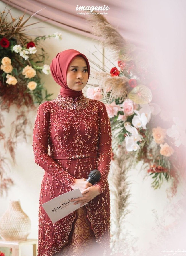 Dipenuhi dengan payet, kebaya tunik berkerah model cheongsam dan berwarna merah marun itu terlihat cantik dan elegan. Bagian depannya tampak memiliki belahan. Dipadukan dengan kain bawahan bermotif yang berwarna senada, penampilan Alca jadi semakin mempesona. Foto: Instagram/@dindafirdausa.kebaya