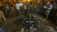 Petugas polisi dan petugas penyelamat memeriksa kendaraan yang rusak di lokasi ledakan bom di Karachi, Pakistan, Senin (16/5/2022) waktu setempat,  