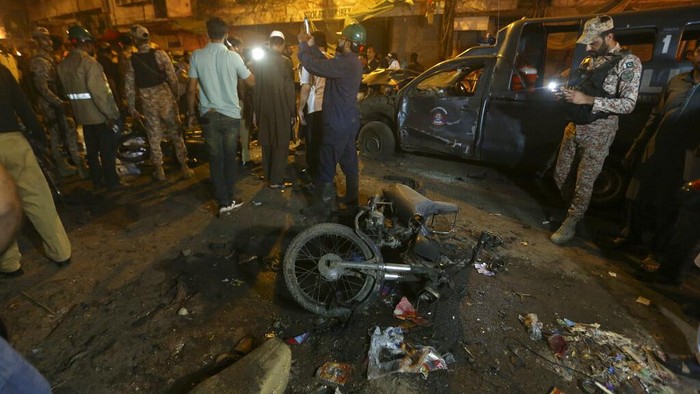 Police officers and and rescue workers examine a damage vehicle at the site of bomb explosion in Karachi, Pakistan, Monday, May 16, 2022. A roadside bomb went off near a police van in the southern port city of Karachi killing and wounding few people, senior police official Ali Mardan Khoso said. (AP Photo/Fareed Khan)