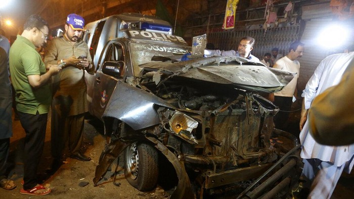 Police officers and and rescue workers examine a damage vehicle at the site of bomb explosion in Karachi, Pakistan, Monday, May 16, 2022. A roadside bomb went off near a police van in the southern port city of Karachi killing and wounding few people, senior police official Ali Mardan Khoso said. (AP Photo/Fareed Khan)