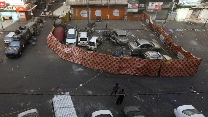 Police officers and and rescue workers examine a damage vehicle at the site of bomb explosion in Karachi, Pakistan, Monday, May 16, 2022. A roadside bomb went off near a police van in the southern port city of Karachi killing and wounding few people, senior police official Ali Mardan Khoso said. (AP Photo/Fareed Khan)
