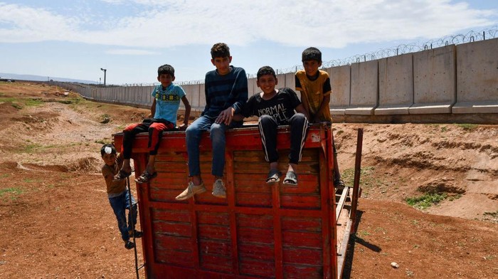 Camp children play on the wall separating Syria and Turkey near the town of Atma in Idlib countryside, northwest of Syria, on May 17, 2022. (Photo by Rami Alsayed/NurPhoto via Getty Images)