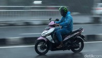 Pengendara yang membawa mantel nekat menerobos hujan deras di Jalan Kramat Raya, Jakarta.