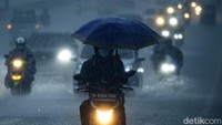 Meski berbahaya, pengendara ini tetap nekat menerobos hujan dengan menggunakan payung.