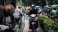 Selain pengendara motor, tampak pesepeda menaiki trotoar. Kemudian mereka turun kembali saat tiba di lampu merah.