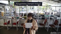 Seorang calon penumpang di di Stasiun Pasar Senen menunjukan berkas antigen.