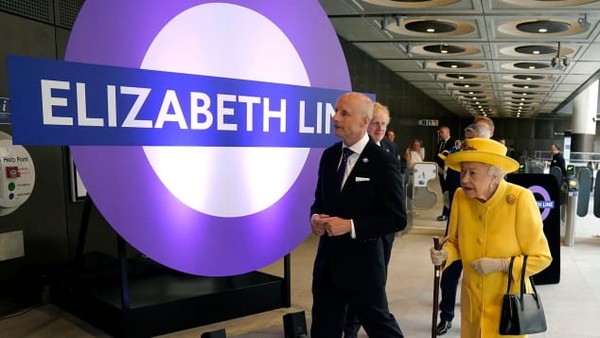 Memakai outfit berwarna kuning dan topi kuning cerah, Ratu Inggris Elizabeth II muncul di tengah publik. Kehadirannya pada perayaan pembukaan jalur kereta ini mengejutkan semua orang. (Andrew Matthews/Getty Images via CNN)