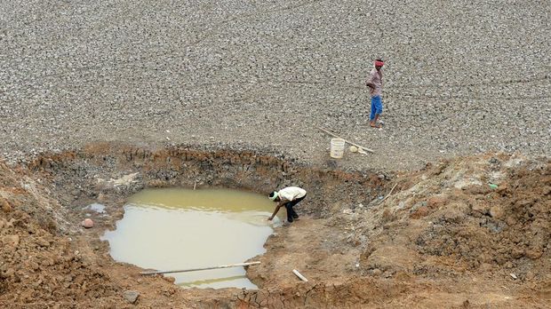 Seorang pekerja India mengumpulkan sedikit air terakhir di kolam terakhir di Waduk Puzhal yang mengering di pinggiran Chennai. (via Getty Images/ARUN SANKAR)