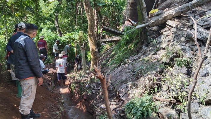 Warga saat melakukan gotong royong untuk membersihkan beberapa material yang menutup saluran irigasi akibat jebolnya senderan.