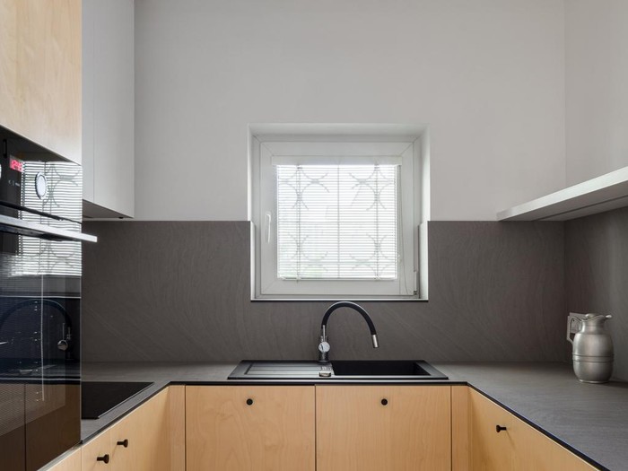 Minimal style black kitchen 3d render.There are white floor and wall, Glossy white cabinet doors,Black refrigerator and oven,The room has large windows. lookink out to the city view.