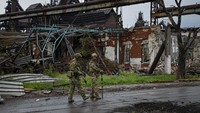 Dua prajurit militer Rusia berpatroli di area Pabrik Metalurgi Illich Iron & Steel Works yang hancur imbas perang Rusia-Ukraina di Mariupol, Rabu (18/5/2022).