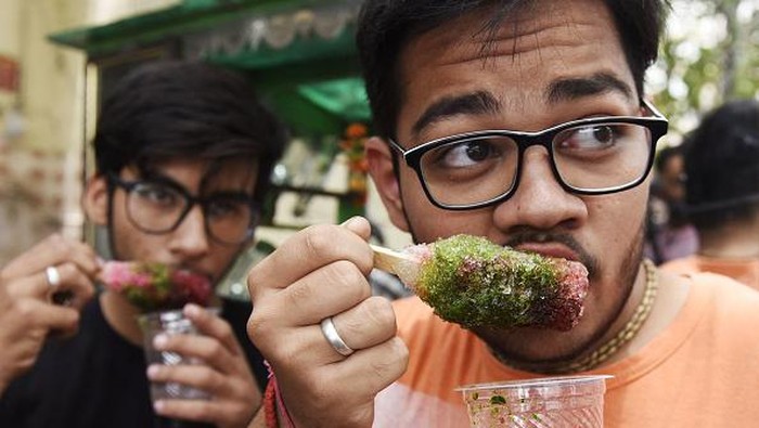 India Panas Banget, Orang-orang Berebut Minum Es Youths enjoy an ice popsicle during a hot summer day in Amritsar on May 18, 2022. (Photo by NARINDER NANU / AFP) (Photo by NARINDER NANU/AFP via Getty Images)