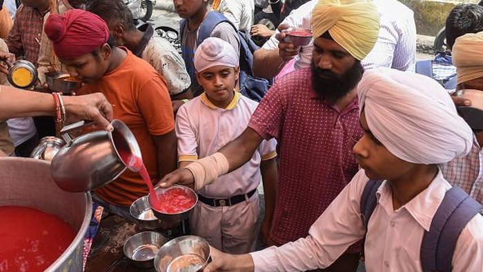 India Panas Banget, Orang-orang Berebut Minum Es Youths enjoy an ice popsicle during a hot summer day in Amritsar on May 18, 2022. (Photo by NARINDER NANU / AFP) (Photo by NARINDER NANU/AFP via Getty Images)