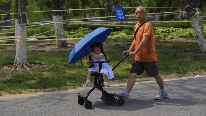 Taman di China Penuh Barikade, Ada Apa? A resident pushes a child past the green space barricaded to prevent residents from gathering due to pandemic measures on Thursday, May 19, 2022, in Beijing. (AP Photo/Andy Wong)