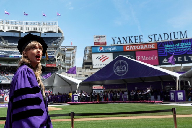 Taylor Swift hadir memakai seragam wisuda sama seperti wisudawan dan wisudawati lainnya di Universitas New York. Dia mengenakan baju wisuda ungu dan hitam khas Universitas New York dan toga di kepalanya.  Foto: REUTERS/Shannon Stapleton